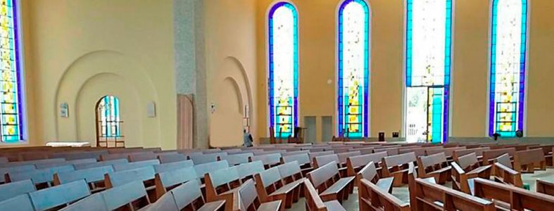 Bancos para Igreja curvos, em madeira maciça, iluminados por vitrais religiosos na técnica de chumbo